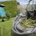 Compost shredder on lawn behind sack of clippings.