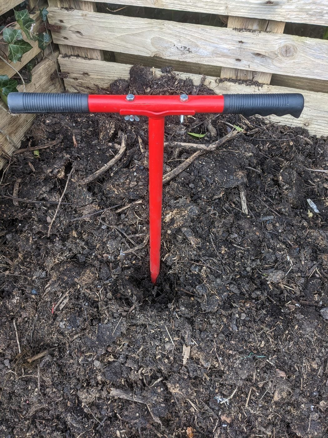 A compost aerator pushed down into a compost heap